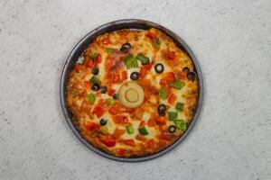 vegetable pizza topping with olives, tomato, onion, cucumber, mushroom and cheese served in dish isolated on grey background top view of bangladeshi fastfood photo
