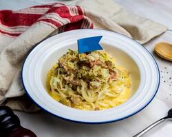 Grilled Carbonara Chicken with Fish Udon served in plate isolated on napkin side view italian cuisine on table photo