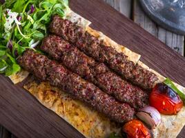 Iraqi beef seekh kabab platter served in dish side view on wooden table background photo