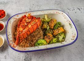 A la parrilla langosta cola con frito arroz, A la parrilla maíz y brócoli servido en aislado en gris antecedentes parte superior ver de singapurense comida foto