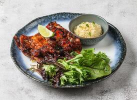 chao ta grilled pork ribs with plai rice, lemon and green leaves served in dish isolated on grey background top view of singapore food photo