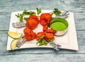 chicken lollipop or lollypop with chutney sauce served in dish isolated on wooden table top view of indian spicy food photo