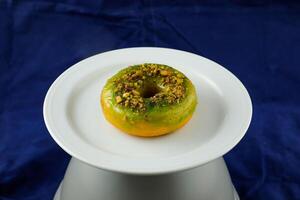 Lemon Pistachio Donut served in plate Isolated on blue background side view of baked breakfast food photo