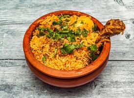 chicken hyderabadi biryani served in claypot isolated on wooden table top view of indian spicy food photo