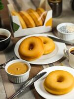 Plain Donuts with dip and cup of coffee isolated on napkin side view of baked food breakfast on table photo