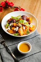 Roasted Vegetables, Feta Crumble and Citrus Salad served in bowl with flowers and fork isolated on napkin side view of healthy green food on table photo