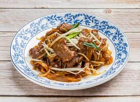 fried hor fun with beef served in dish isolated on wooden table top view hong kong food photo