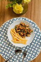 Fried Calamari with french fries, spoon and fork served in dish isolated on table top view of fastfood appetizer photo