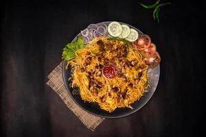 Chicken chow mein with capsicum, tomato, cucumber, onion and chilli sauce served in dish isolated on napkin dark background top view of indian fastfood photo