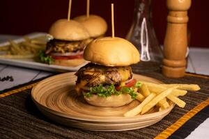 Beef Sliders include onion, tomato, lettuce leaf and french fries served in dish isolated on napkin side view on wooden table italian food photo