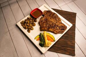 T Bone steak grilled meat with sauce, mushroom and salad served in dish isolated on napkin side view on wooden table italian food photo