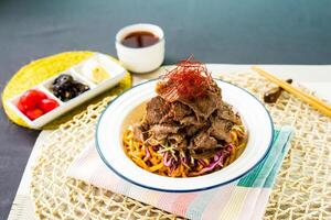 Sichuan Spicy Braised Beef with Fish Udon with chopstick served in bowl isolated on napkin side view of japanese food on table photo