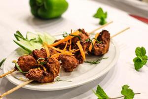 Chicken tikka boti kabab with salad, carrot and cucumber served in dish isolated on table side view of indian spices food photo