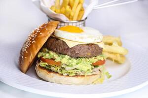 beef burger with sunny side up egg and french fries bucket served in dish isolated on table side view of arabic food photo