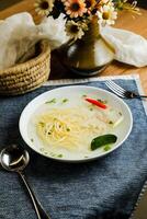 Clear Lemon Chicken Wonton include noodles, spring onion and red pepper served in bowl isolated on napkin side view of chinese soup photo