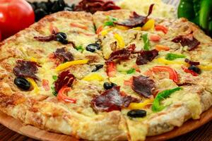 Pastrami and eggs pizza pie with bell pepper, tomato and black olive served in wooden board isolated on table side view of arabic food photo