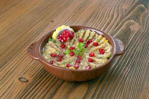 mutabal with pomegranate seeds and lemon slice served in dish isolated on table side view of arabic food photo