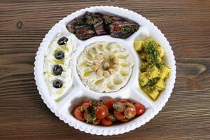 Mix salads with hummus, cherry tomato, potato, olive, chickpeas and meat platter served in dish isolated on table top view of arabic food photo