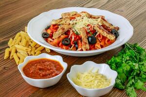 Tomato sauce pasta with chili sauce, chicken, olives and coriander served in dish isolated on table top view of arabic food photo