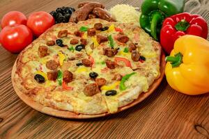 Sausage and minced meat pizza pie with bell pepper, tomato and black olive served in wooden board isolated on table side view of arabic food photo