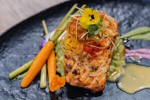 chamuscado crujiente piel salmón filete con salsa, Zanahoria y flor servido en plato aislado en mesa lado ver de Mariscos principal curso Arábica comida foto