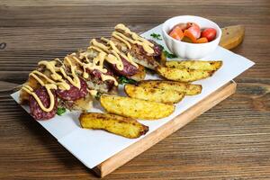 Hawawshi, smoked salami and cheese with potato veggies and cherry tomato served in cutting board isolated on wooden table side view of arabic food photo