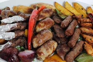 t kebab, chicken, beef, mutton, potato veggies, tomato and onion served in dish isolated on table top view of arabic food photo