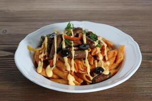 Sausage pasta and cheese with black olive served in dish isolated on table top side view of arabic food photo