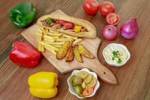 Arabic Shish Tawook Sandwich with bell pepper, onion, tomato, dip, hummus, veggies and fires isolated on wooden board side view arabic fastfood photo