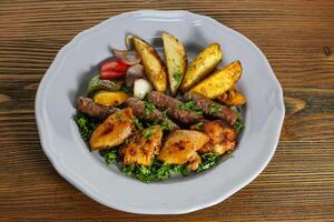 Mix kofta and shish tawook kabab with potato veggies, tomato, onion and coriander served in dish isolated on table side view of arabic food photo