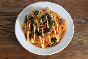 Sausage pasta and cheese with black olive served in dish isolated on table top view of arabic food photo