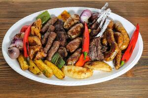 Mix grill family platter tikka kabab, lamb chop, meat kebab, chicken, beef, mutton, potato veggies, tomato and onion served in dish isolated on table top view of arabic food photo