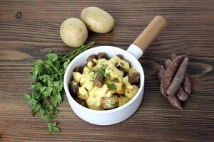 Sausage, potatoes and cheese with coriander served in dish isolated on wooden table side view of arabic food photo