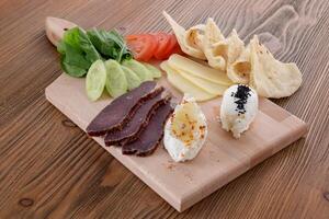 Mix cheese with tomato, cucumber and pita bread served in wooden board isolated on table side view of arabic food photo