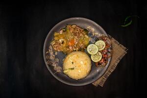 chicken vegetable fried rice with carrot, tomato, cucumber, egg, and green chilli served in dish isolated on napkin dark background top view of indian fastfood photo