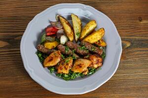 mezcla kofta y shish tawook kabab con patata verduras, tomate, cebolla y cilantro servido en plato aislado en mesa parte superior ver de Arábica comida foto