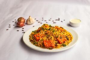 Mughlai Paneer tikka Biryani rice pulao with garlic, onion and raita served in plate isolated on background side view of indian and pakistani traditional food photo