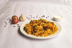 Mughlai Beef Biryani rice pulao with garlic, onion and raita served in plate isolated on background side view of indian and pakistani traditional food photo