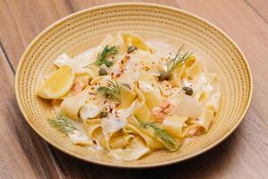 Pappardelle al Salmone or Tagliatelle noodles with lemon served in plate isolated on table side view of italian fastfood photo