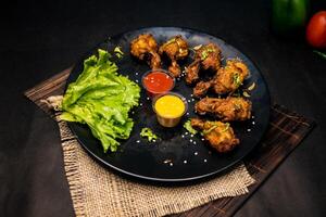 Tandoori Chicken Lollipop with mayo dip chilli sauce served in dish isolated on napkin dark background top view of indian fastfood photo