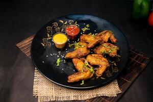 caliente pollo alas con chile salsa y mayonesa inmersión servido en plato aislado en servilleta oscuro antecedentes parte superior ver de indio comida rápida foto