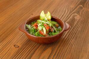 Fresh green salad of cucumber, tomato, onion and coriander served in dish isolated on wooden table side view of arabic food photo