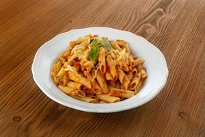Pasta with chili sauce served in dish isolated on wooden table side view of arabic food photo