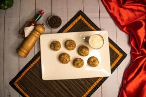 Stuffed Mushroom with shrimp meat balls dumplings with dip, black pepper and garlic chilli sauce served in dish isolated on napkin top view on wooden table italian food photo