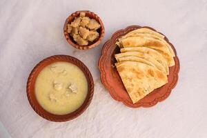 desi breakfast Chicken soup, Halwa and paratha served in dish isolated on background top view of bangladesi breakfast photo