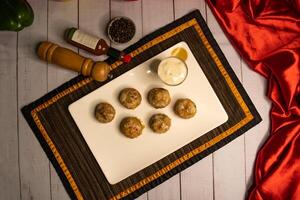 Stuffed Mushroom with shrimp meat balls dumplings with dip, black pepper and garlic chilli sauce served in dish isolated on napkin closeup top view on wooden table italian food photo