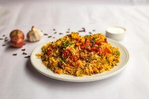 Mughlai Chicken tikka Biryani rice pulao with garlic, onion and raita served in plate isolated on background side view of indian and pakistani traditional food photo