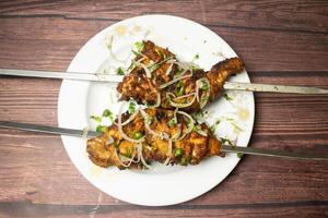 Tandoori Chicken served in dish isolated on wooden table top view indian spices food photo