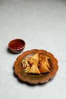 crujiente samosa lleno con pollo y vegetales con chile salsa tomate salsa de tomate servido en plato aislado en mesa parte superior ver de indio, bangladeshi y pakistaní calle comida foto