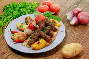 kofta kebab miced meat kabab with tomato, onion potato and coriander served in dish isolated on table side view of arabic food photo